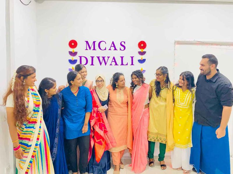 MCAS team celebrating Diwali in front of an MCAS backdrop