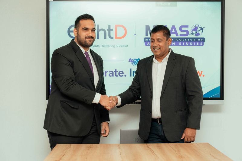 MCAS and EightD representatives shaking hands at a collaboration signing
